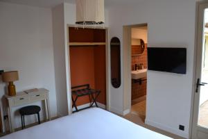 Dormitorio con cama, escritorio y TV en Hôtel La Garrigue & Bar Piscine, en Venasque