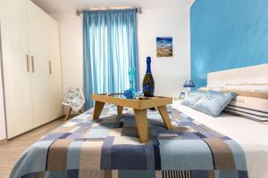 サン・ヴィート・ロ・カーポにあるCasa Vacanze Il Faro San Vito Lo Capo-Trapani-Sicilia Ovest Holiday Homeのベッドルーム1室(ベッド1台、ワイン1本とテーブル付)