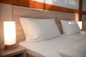 1 cama con almohada blanca y lámpara en Vadkacsa Panzio, en Balatonkenese