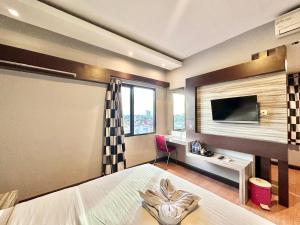 Schlafzimmer mit einem Bett, einem Schreibtisch und einem TV in der Unterkunft My Home Hotel Pontianak in Pontianak