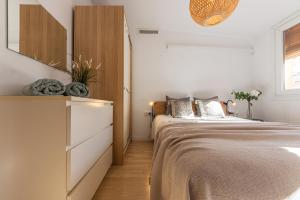 a bedroom with a bed with a dresser and a mirror at GROOOVY Dúplex amb Terrassa in Tarragona