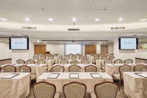 une salle de conférence avec des tables, des chaises et des écrans dans l'établissement Beach Resort Green Bay, à Wanli