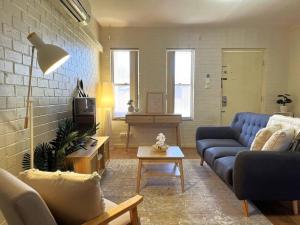 a living room with a blue couch and a table at Beautifully Styled 3 Bedroom Apartment in South Hedland