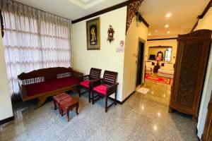 una habitación con piano y sillas y un dormitorio en Baan Rim Kwai Paerimnam Resort en Kanchanaburi