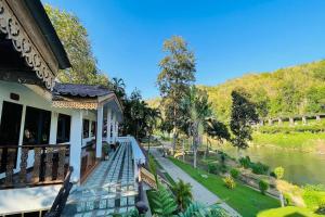 un edificio con una pasarela junto a un río en Baan Rim Kwai Paerimnam Resort, en Kanchanaburi