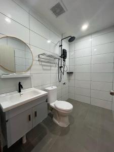 Un baño con inodoro, lavabo y espejo. en Halo Hotel, en Semporna