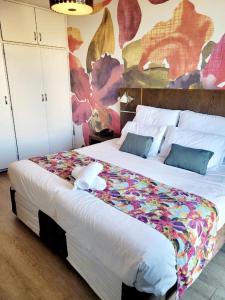 een slaapkamer met een groot bed met een bloemendeken erop bij The Oceanic Self Catering Apartment in Durban
