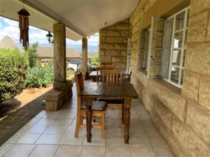 una casa con patio con mesa de madera y sillas en Bird Haven Guesthouse en Leribe