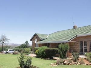 una casa con techo verde y patio en Bird Haven Guesthouse, en Leribe