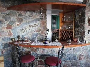 eine Bar in einer Steinmauer mit zwei roten Stühlen in der Unterkunft Grammatikis house in Vourliótai