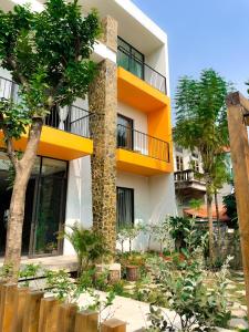 biały budynek z żółtym balkonem i drzewami w obiekcie Trang An Cozy House w mieście Diếm Xá