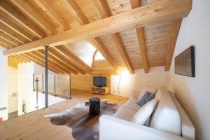 a living room with a white couch and wooden ceilings at Chasa Capricornin in Scuol