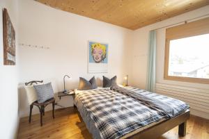 a bedroom with a bed and a desk and a window at Chasa Capricornin in Scuol