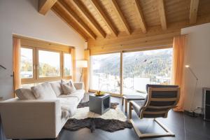 a living room with a white couch and a chair at Chasa Capricornin in Scuol