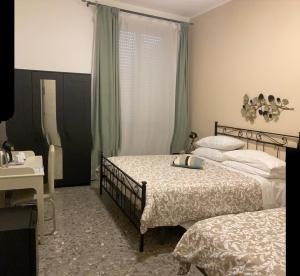 a bedroom with two beds and a desk and a window at Puccini Inn Catania centro in Catania