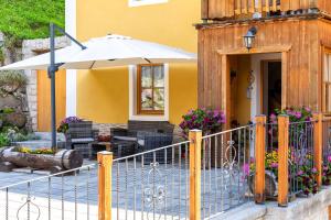 a yellow house with a fence and an umbrella at Cesa Raggio di Sole Bilocale in Livinallongo del Col di Lana