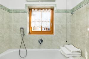 ein Bad mit einer Badewanne und einem Fenster in der Unterkunft Cesa Raggio di Sole Bilocale in Livinallongo del Col di Lana