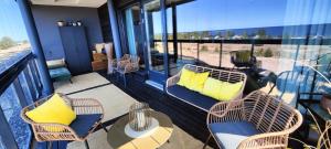 Timantti Apartments by Hiekka Booking في كالايوكي: شرفة مع كراسي الخوص وطاولة مع الوسائد الصفراء