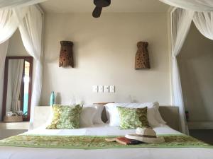 Un dormitorio con una gran cama blanca con sombreros. en Casa Babi, en Vilanculos
