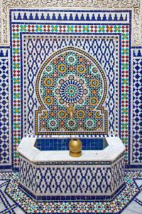 a bathroom with a tub with a tile wall at Riad Rayhana in Fès