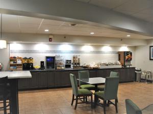 a restaurant with a table and chairs and a kitchen at Best Western Owego Inn in Owego
