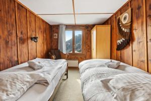 - 2 lits dans une chambre dotée de murs en bois dans l'établissement Chalet spacieux et pittoresque, à Leytron