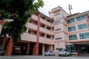un edificio rosa con due auto parcheggiate di fronte di The Infinity Suite Chiangrai a Chiang Rai