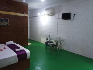 Habitación con cama, mesa y TV. en Hotel Vinchenso en Kaduwela
