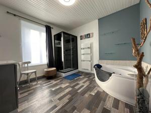 y baño con bañera, mesa y silla. en Maison Kérity with Jacuzzi – Terrace, en Paimpol