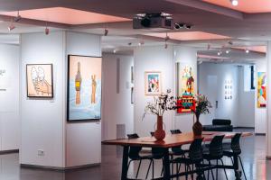 une chambre avec une table, des chaises et des peintures dans l'établissement art'otel amsterdam, Powered by Radisson Hotels, à Amsterdam