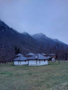 un antiguo edificio en un campo con montañas en el fondo en Rafting Camp Konak, en Foča