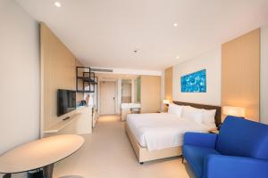 a hotel room with a bed and a blue couch at Resort's full Service Apartment - near the airport Cam Ranh, Nha Trang, Khanh Hoa in Miếu Ông