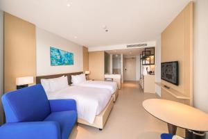 Miếu ÔngにあるResort's full Service Apartment - near the airport Cam Ranh, Nha Trang, Khanh Hoaの大きなベッドと青い椅子が備わるホテルルームです。