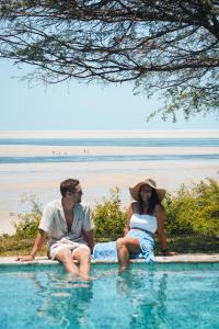 un hombre y una mujer sentados en una piscina en Casa Babi, en Vilanculos