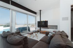 ein Wohnzimmer mit einem Sofa und einem Flachbild-TV in der Unterkunft Seaside Luxury Villa in Paralimni