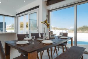 ein Esszimmer mit einem Tisch, Stühlen und Fenstern in der Unterkunft Seaside Luxury Villa in Paralimni