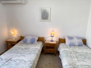 2 camas en una habitación con 2 lámparas en las mesas en Maison authentique avec grande terrasse en Kritinía