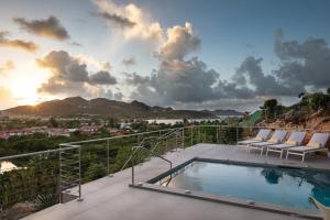 a swimming pool on a patio with chairs and the sunset at Luxury Vacation Villa 15 in Saint Barthelemy