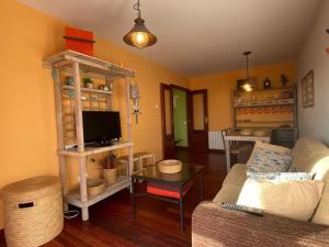 Una sala de estar con un sofá y un televisor. en Los caballos beach apartment, en Cuchía