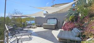 a patio with a tub and chairs and an umbrella at Jacuzzi, summer kitchen, gardens, 20m to beach - Villa Casa Plaza in Seget Vranjica