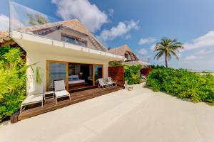 ein Haus am Strand mit Stühlen und Bäumen in der Unterkunft Cinnamon Velifushi Maldives in Felidhoo 