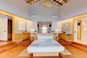 Schlafzimmer mit einem großen weißen Bett und Holzböden in der Unterkunft Cinnamon Velifushi Maldives in Felidhoo 