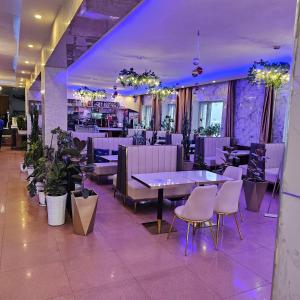 un restaurante con iluminación púrpura, mesas y sillas en Land Hotel, en Ulán Bator