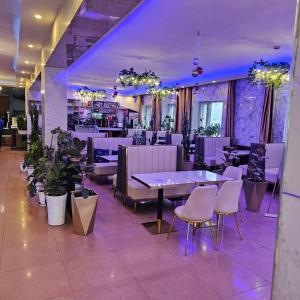 a restaurant with purple lighting and tables and chairs at Land Hotel in Ulaanbaatar