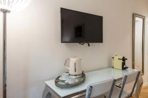 Geranimus Versailles Charost في فرساي: طاولة مع آلة صنع القهوة وتلفزيون على الحائط