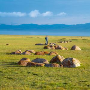 a man standing on top of a field with rocks at Ulush Yurts in Naryn