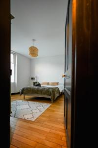 a bedroom with a bed on a wooden floor at La maison Janisse - gîte en centre-ville avec jardin in Limoges