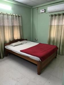 ein Schlafzimmer mit einem Bett mit einer roten Decke darauf in der Unterkunft Suryalaxmi guest house in Guwahati