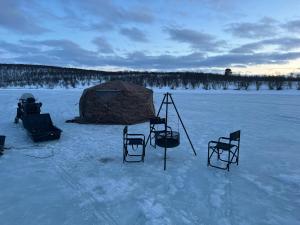 a group of chairs and a tent in the snow at Aurora Tent Camp in Karasjok