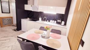 a kitchen with a table and chairs and a kitchen with white cabinets at Apartament Black-White in Mielno